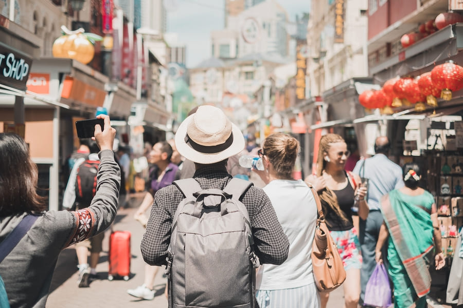 Un viajero con mochila y sombrero de paja explora una animada calle de China